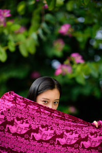 Portrait of young woman covering face with scarf at park