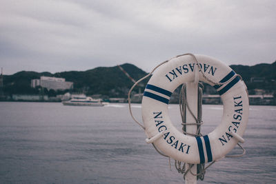 Information sign by sea against sky