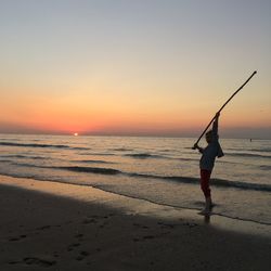 Man on beach against sky during sunset