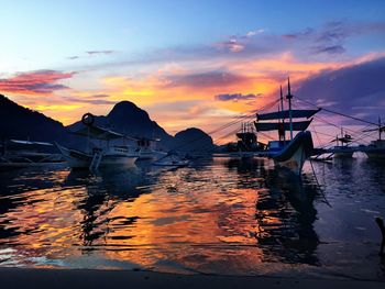 Boats in sea at sunset