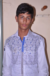 Portrait of young man standing against wall