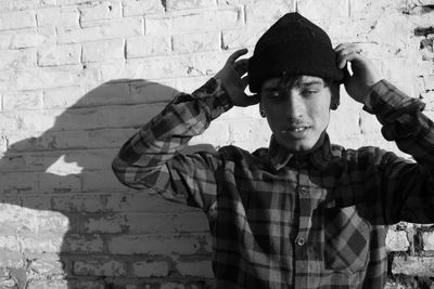 Portrait of young man standing against wall