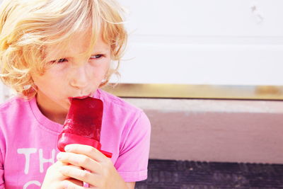 Blond boy eating flavored ice outdoors