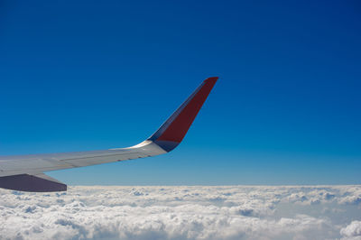 Low angle view of airplane wing against clear blue sky