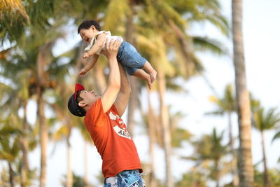 Man playing with baby boy against trees