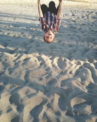 Boy playing on swing over sand at park