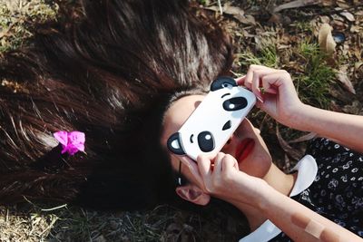 Woman covering eyes with mobile phone on field