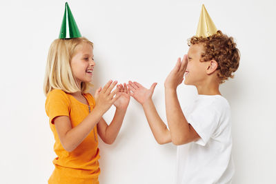 Sibling wearing party hat against white background