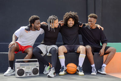 Multi-ethnic friends with basketball listening to music