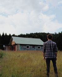 Rear view of man standing on field against sky