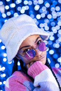 Joyful woman of color with a white beanie braided hairstyle and pink glasses enjoying the christmas 