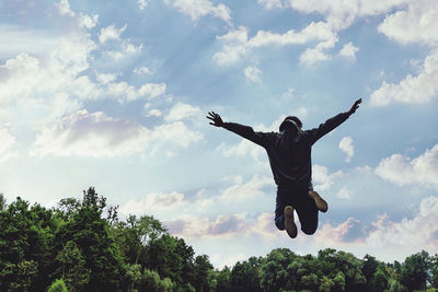 Low angle view of man jumping against sky