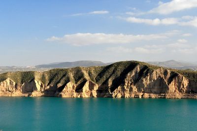 Scenic view of river by mountains against sky