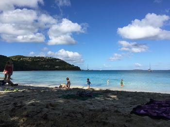 People at beach against blue sky