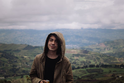 Portrait of young man standing against mountains