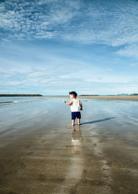 Full length of man standing on beach against sky