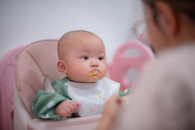 Close-up of cute baby girl sitting on bed at home