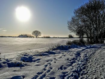 Scenic view of frozen landscape against sky during winter
