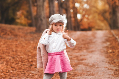 Cute girl showing ok sign gesture standing in park