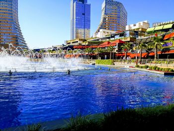 Water fountain in swimming pool against buildings in city