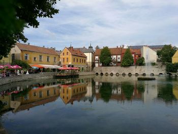 Reflection of houses on lake against sky