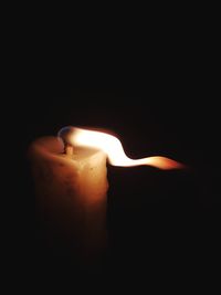 Close-up of lit candle in darkroom