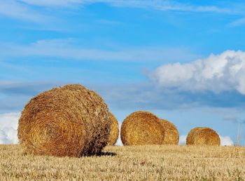 Hay bales on field against sky