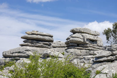 Stack of stones on rock against sky