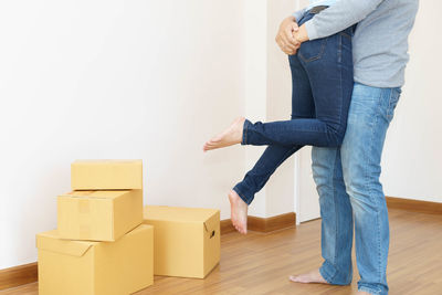 Low section of woman standing on hardwood floor at home