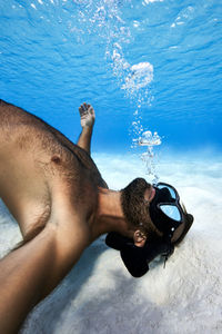 Midsection of shirtless man swimming in sea