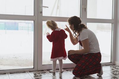 Side view of mother and daughter walking on window