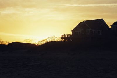 Silhouette houses against sky during sunset