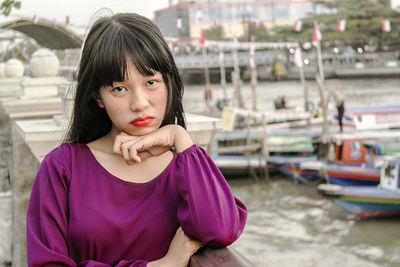 Portrait of woman by railing against boats on river