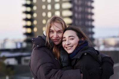 Portrait of smiling female couple against apartment block