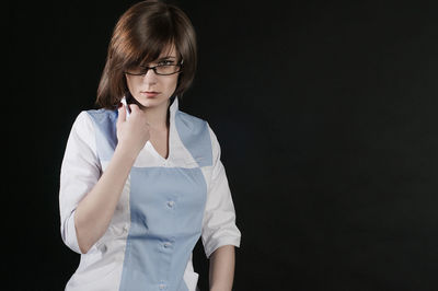 Portrait of beautiful woman standing against black background