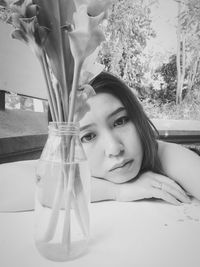 Portrait of young woman on table by window