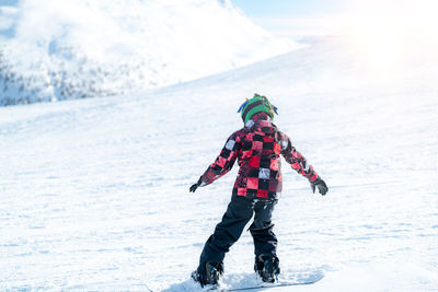 Cute boy snowboarding down the slope