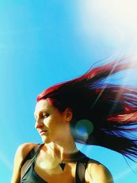Portrait of young woman looking away against blue sky