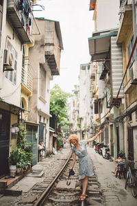 Woman walking on railroad track amidst buildings