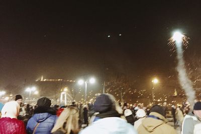 Crowd at music concert against sky at night