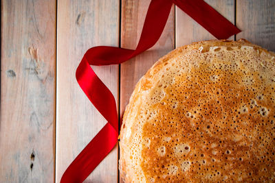 Traditional russian thin pancakes closeup on a light wooden background and a red ribbon.