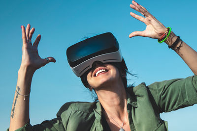 Low angle view of woman using virtual reality simulator against sky