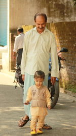 Full length of boy with grandfather walking on road