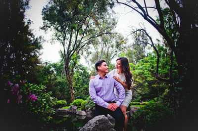 Young couple smiling against trees