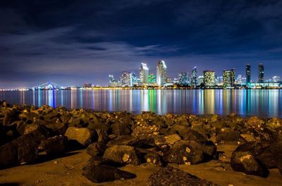 Illuminated cityscape against cloudy sky