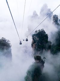 Low angle view of overhead cable cars against sky