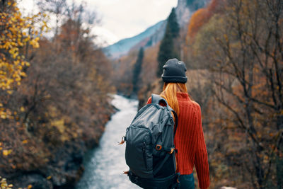 Rear view of person standing on rock during autumn