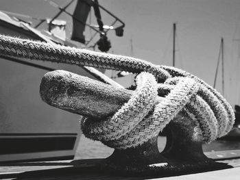 Close-up of rope tied on bollard by boat moored at harbor