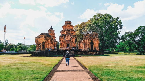 Rear view of woman walking towards temple on footpath