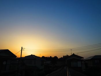 Silhouette houses against sky during sunset